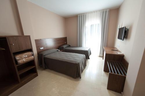 a hotel room with two beds and a window at Visit Hotel in Caspe