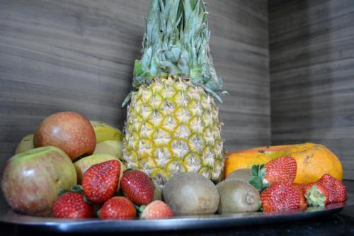 a pile of fruit on a plate with a pineapple at Hotel Consalter in Rodeio Bonito