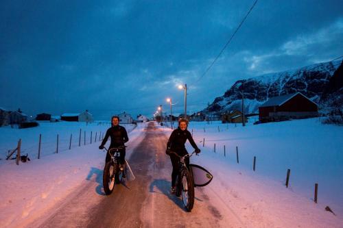 two people riding bikes down a snow covered road at Unstad Arctic Resort in Unstad