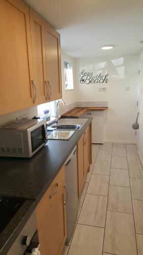 a kitchen with a counter top with a microwave at 1 bed self catering apartment in Weymouth