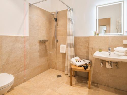 a bathroom with a shower and a sink and a toilet at Hotel Landhaus Ammann in Hannover