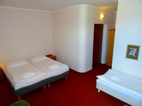 a bedroom with two beds and a red carpet at Hotel Bartis in Bartoszyce