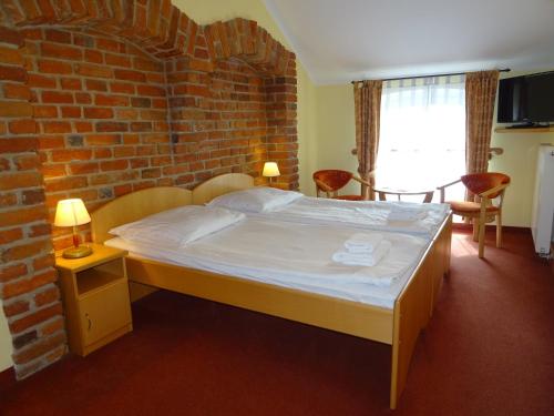 a bed in a room with a brick wall at Hotel Bartis in Bartoszyce