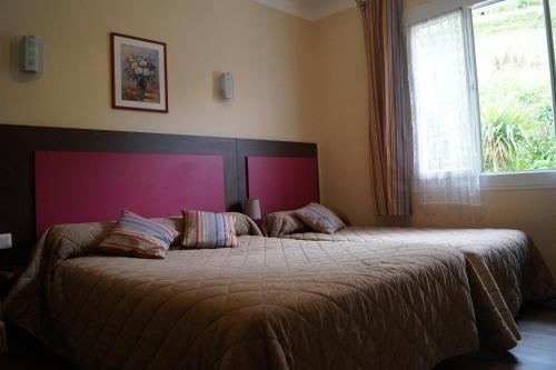 a bedroom with a large bed with a large window at Les Sources de La Nive in Esterençuby