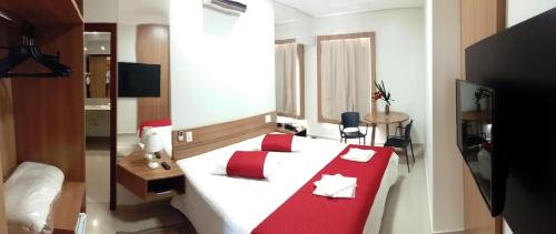 a bedroom with a large white bed with red pillows at Guines Palace Hotel in Patrocínio