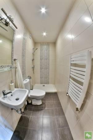 a white bathroom with a sink and a toilet at Willa polne wzgórza in Krynica Zdrój