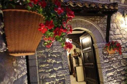 a walkway with flowers hanging from a stone wall at Hotel Vila Aleksander in Berat