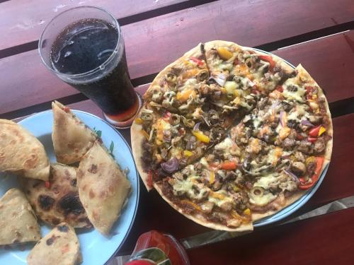 a pizza on a table with two plates of food at Mount nature villa in Hikkaduwa