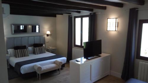 a bedroom with a bed and a flat screen tv at Hotel Resort Cueva del Fraile in Cuenca
