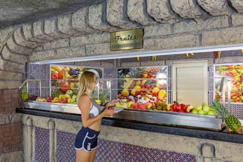 a woman is standing in front of a fruit stand at Royal Holiday Palace in Lara