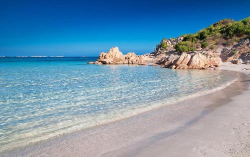 a sandy beach with rocks in the water at B&B Luce Viola in Dorgali
