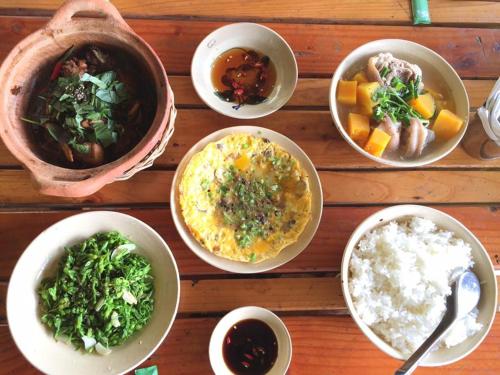 a wooden table topped with bowls of food and other foods at Happy Farm Tien Giang Homestay in My Tho