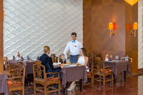 a man standing at a table in a restaurant at Royal Holiday Palace in Lara