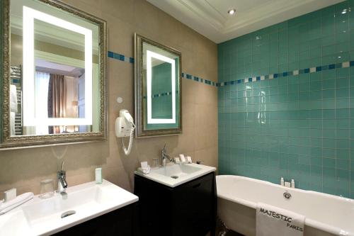 a bathroom with a sink, mirror, and bathtub at Majestic Hotel Spa - Champs Elysées in Paris