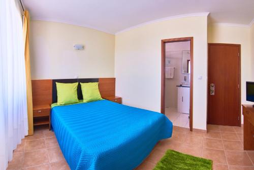 a bedroom with a blue bed and a television at Alojamento Bela Vista in Lajes do Pico