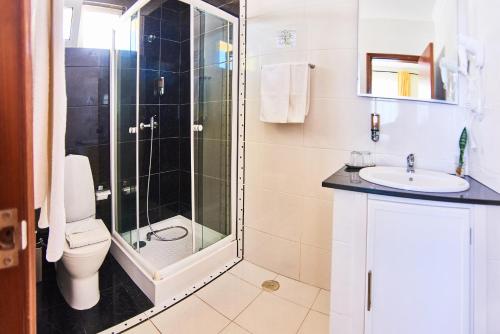 a bathroom with a shower and a toilet and a sink at Alojamento Bela Vista in Lajes do Pico
