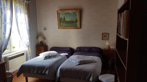 Duas camas individuais num quarto com uma fotografia na parede em Le Moulin em Pontoise-lès-Noyon