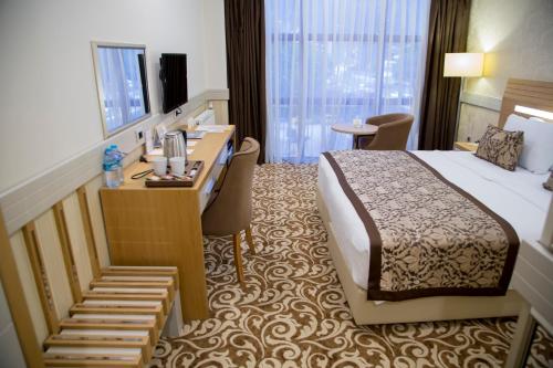 デニズリにあるGrand İtimat Hotelのベッド、デスク、階段が備わるホテルルームです。