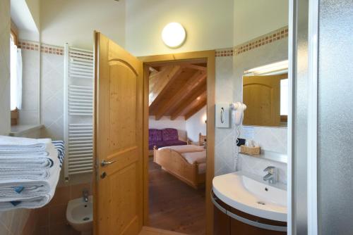 a bathroom with a sink and a toilet and a bedroom at Agritur Maso Chemela in Cavalese