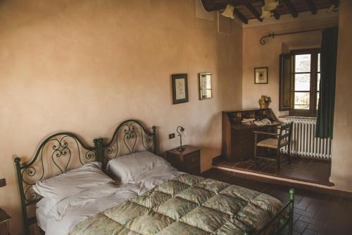 a bedroom with a bed and a desk and a window at Agriturismo Zampugna in Montefollonico