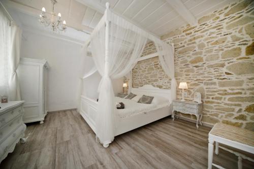 a bedroom with a white bed and a stone wall at Vidéki Varázs Vendégház in Bogács