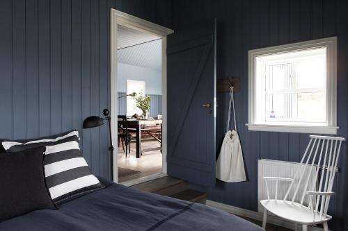 ボルガルネースにあるBlack timber houseの青い壁のベッドルーム1室、ベッド1台、椅子1脚が備わります。