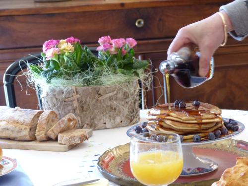 una persona vertiendo jarabe en una pila de panqueques en una mesa en La Mirandole, en Foix