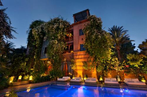 a large swimming pool in front of a large building at Dar Rhizlane, Palais Table d'hôtes & SPA in Marrakech