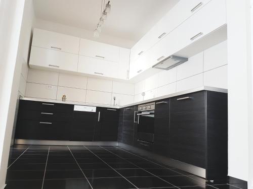 eine Küche mit weißen Schränken und schwarzen Fliesenböden in der Unterkunft Apartments Vila White House in Pančevo