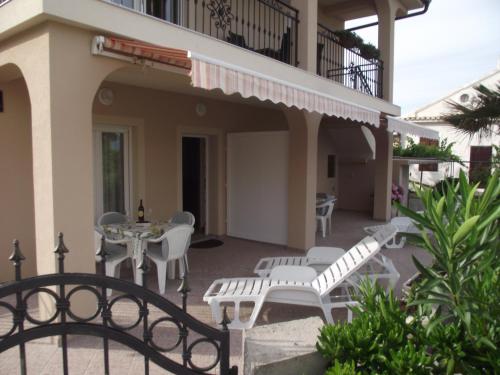 a patio with white chairs and tables on a house at Apartments Dajana Silo in Šilo