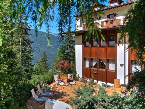 a house with people sitting on a patio in front of it at Hotel Caminetto in Folgarida