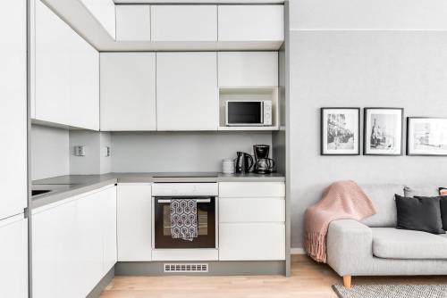 a kitchen with white cabinets and a chair and a couch at Apartment Pohjanpoika in Oulu