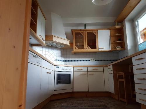 eine kleine Küche mit weißen Schränken und einem Fenster in der Unterkunft Haus Fischer in Dorfgastein