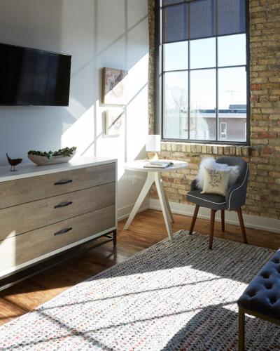 a living room with a tv and a chair and a table at Kinn Guesthouse Bay View in Milwaukee