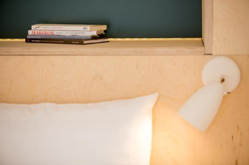 a bed with a pillow and books on a shelf at Isabella Living in Maribor