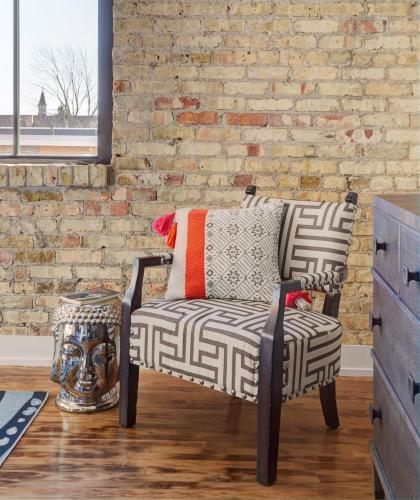 a living room with a chair and a brick wall at Kinn Guesthouse Bay View in Milwaukee