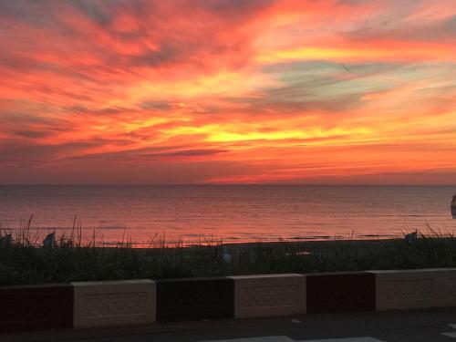 a sunset on the beach with the ocean at Palace Hotel Zandvoort in Zandvoort