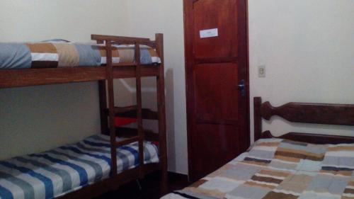 a room with two bunk beds and a door at Pousada Moporã, a antiga pousada do Waldir, com amplas suítes no centro de Aiuruoca in Aiuruoca