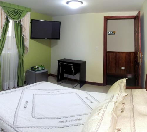 a bedroom with a bed with a desk and a television at Apartahotel Vincent Suites in Pasto