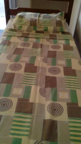 a bed with a quilt on top of it at Pousada Moporã, a antiga pousada do Waldir, com amplas suítes no centro de Aiuruoca in Aiuruoca