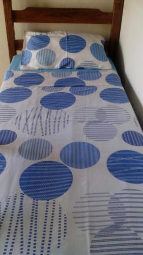 a bed with a blue and white comforter at Pousada Moporã, a antiga pousada do Waldir, com amplas suítes no centro de Aiuruoca in Aiuruoca