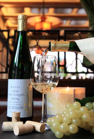 a bottle of wine next to a glass and grapes at Hotel-Restaurant Weinhaus Grebel in Koblenz