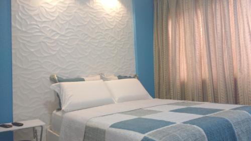 a bedroom with a bed with a checkered blanket at Apartamento Vernazza in Maceió
