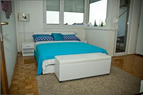 - une chambre avec un lit bleu et une fenêtre dans l'établissement Apartment Pluvia, à Osijek