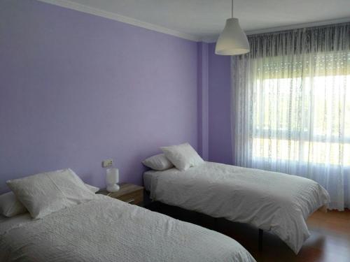 two beds in a bedroom with purple walls and a window at Arzúa Home in Arzúa