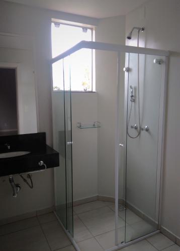 a bathroom with a glass shower and a sink at Hotel Colibris in Lontras