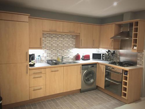 a kitchen with wooden cabinets and a washing machine at Liberty Suite Apartment in Portishead