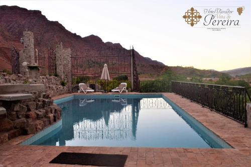 a swimming pool with two chairs and a mountain at Parador Viña de Pereira in Villa Abecia