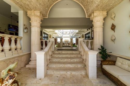 a staircase in a home with columns and a chandelier at Cielo Maya Beach Tulum in Tulum