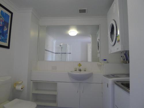 une salle de bain blanche avec un lavabo et un miroir dans l'établissement Santana Resort Surfers Paradise, à Gold Coast